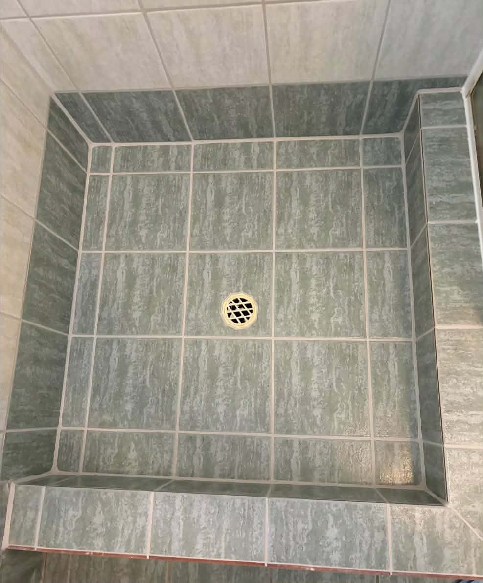 The same shower after regrouting, with fresh clean grout and the original tiles kept
