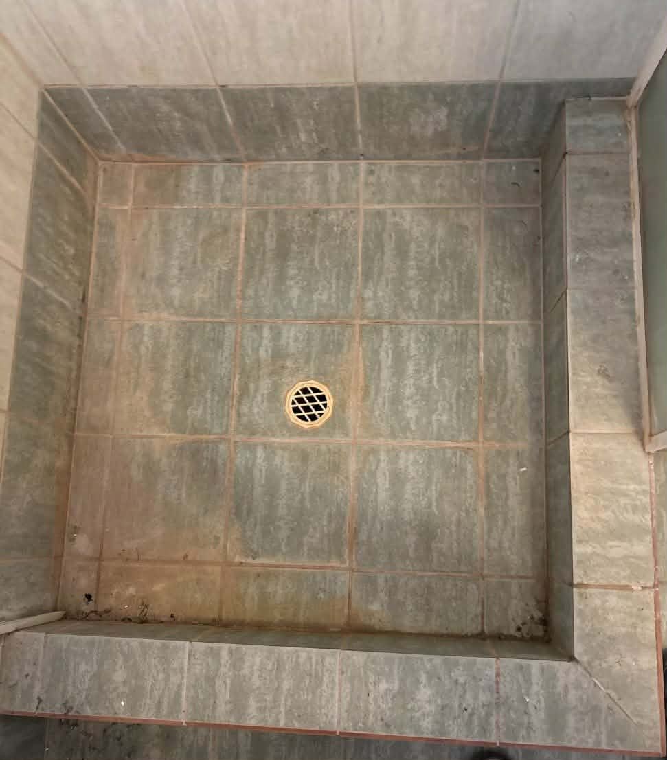 Shower floor with old, worn and stained grout before regrouting